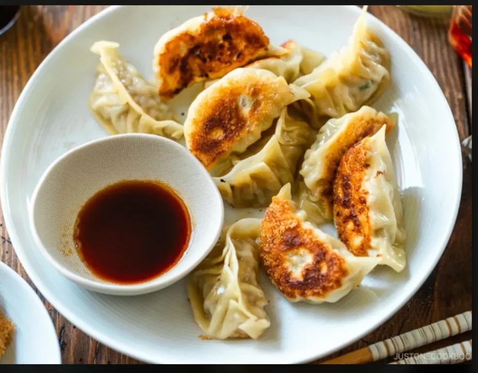 Pan-fried gyoza dumplings served with dipping sauce